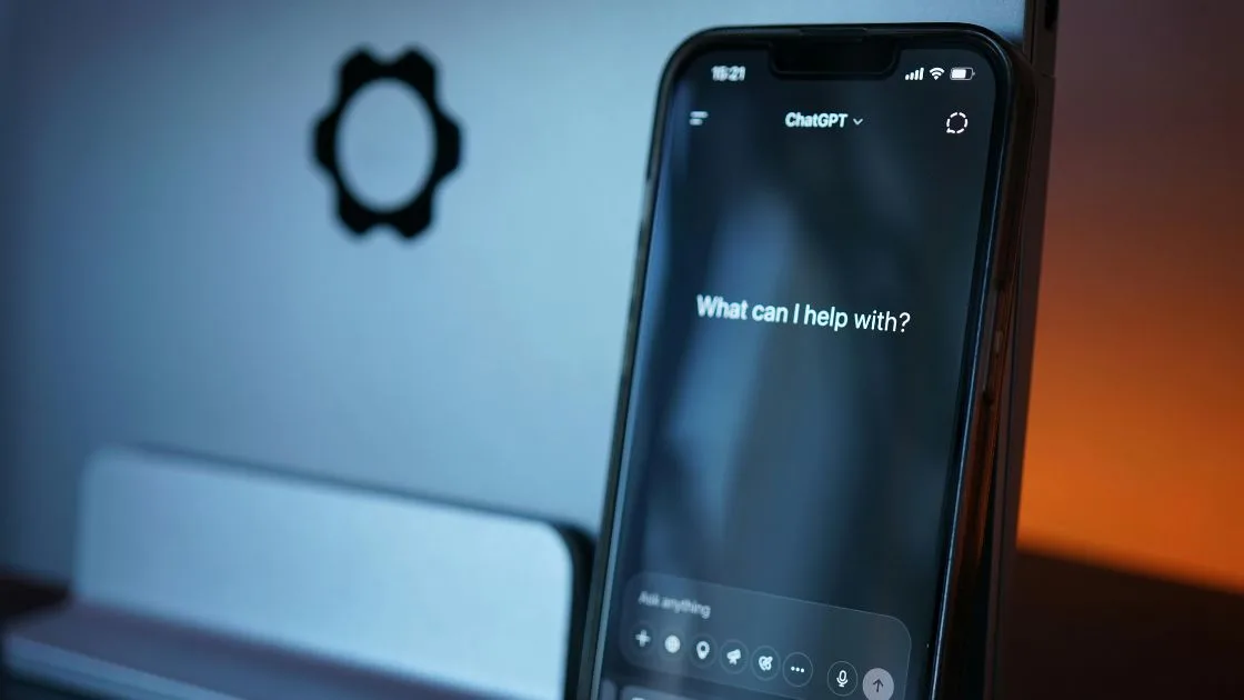 A smartphone showing the ChatGPT app open to the prompt 'What can I help with?'