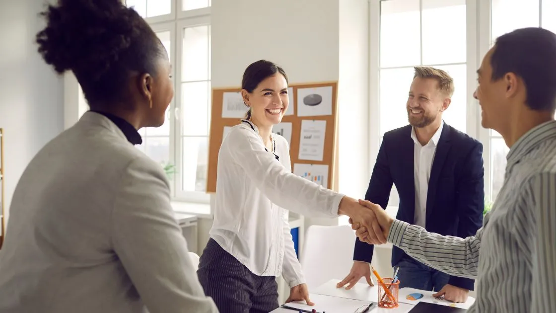 Small business owner shaking hands with a marketing team in a bright Copley, Ohio office