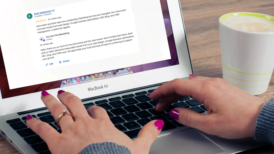 A person using a laptop displaying a five-star Google review for a local business