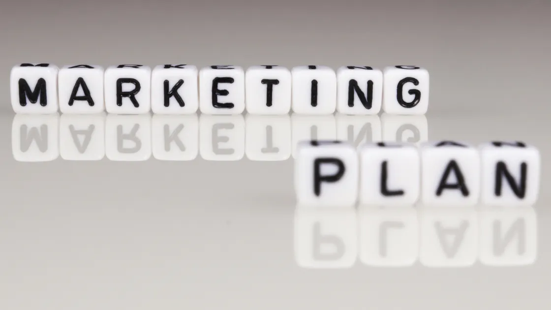 White letter blocks spelling out "Marketing Plan" on a reflective surface
